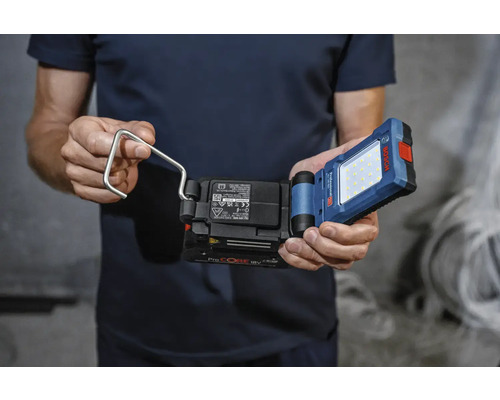 Man håller en batteridriven arbetslampa med krok av märket Bosch.