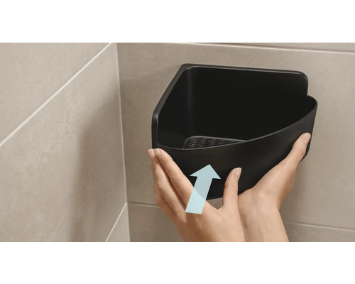 En person fäster en svart hörnhylla i badrummet.