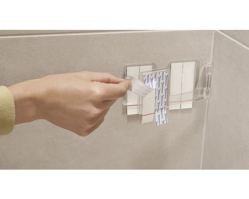 Person tar bort skyddsfilm från självhäftande remsor på ett väggfäste