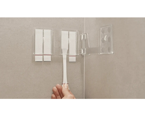 Transparent tandborstmugg med fästband på en badrumsvägg