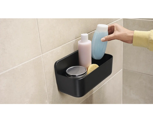 Svart duschkorg med hygienartiklar på väggen