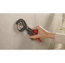 Installatör fäster en rosett på en vägg med en rörtång