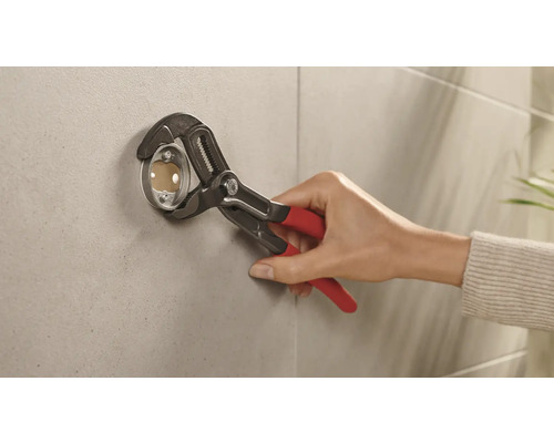 Installatör fäster en rosett på en vägg med en rörtång