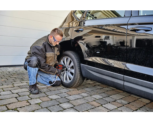 Man byter däck på en bil med en sladdlös mutterdragare.