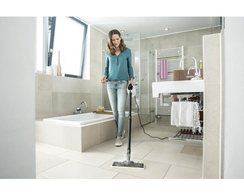 Kvinna rengör badrumsgolvet med en ångtvätt