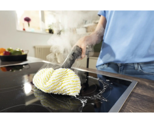 En person rengör en spishäll med en ångtvätt.