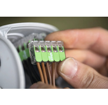 Närbild av en man som ansluter elektriska ledningar med en Wago 221-anslutning