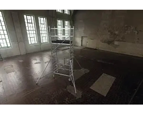 Ställning i ett tomt rum med stora fönster för byggnadsarbete.