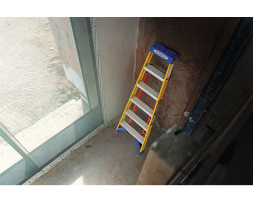 En trappstege står lutad mot en vägg inomhus.