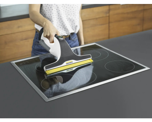 Kvinna rengör glaskeramikhäll med en fönstertvätt