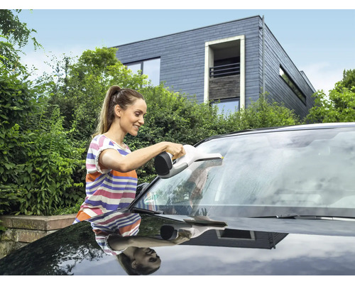 En kvinna rengör vindrutan på en bil med en fönstersug.