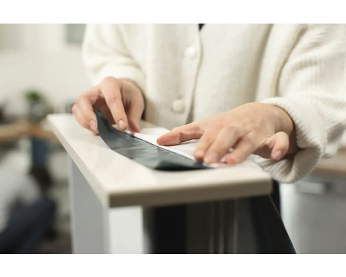 En person applicerar en självhäftande film på en yta.