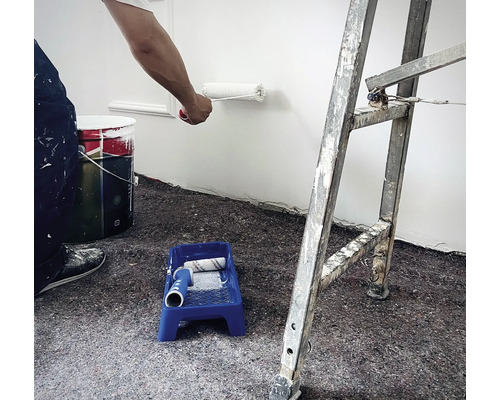 Bild av en vägg som målas med en färgroller, inklusive en färgburk, ett färgtråg och en stege.