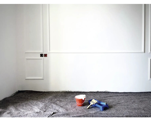 Ett rum med väggpaneler, täckt med målarfilt, färgburk och färgroller