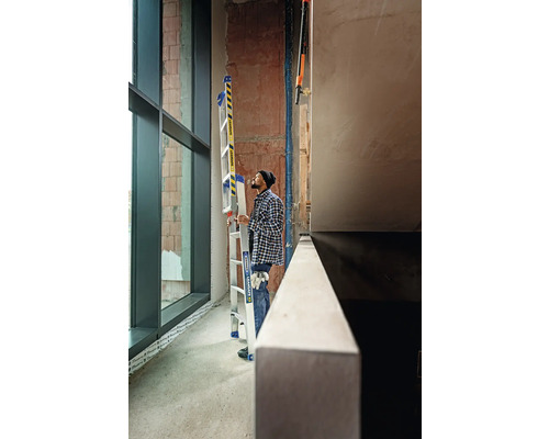 Man med aluminium multifunktionsstege i ett råbygge