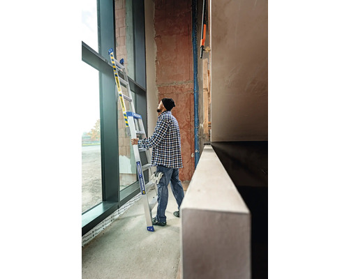 En person håller en multifunktionell stege i ett rum med ett stort fönster.