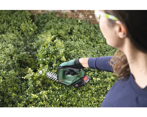 Kvinna klipper häck med sladdlös häcksax