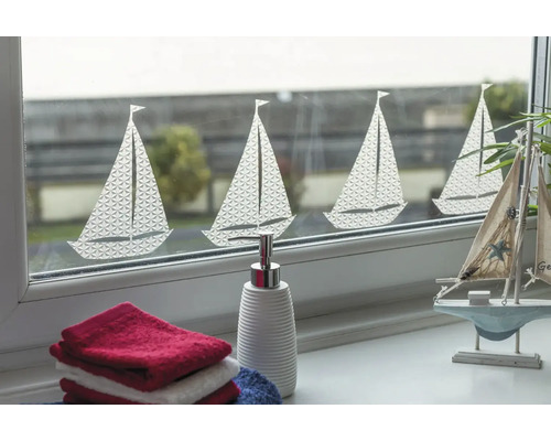 Dekorativt fönster med segelbåtsmotiv, kompletterat med handdukar och en tvålpump