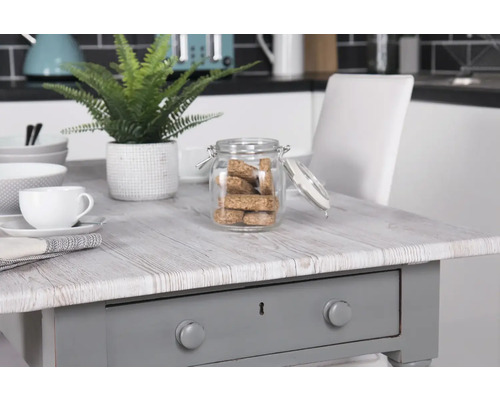 Dekorativt arrangemang med bord, porslin och förvaringsburk i ett kök.