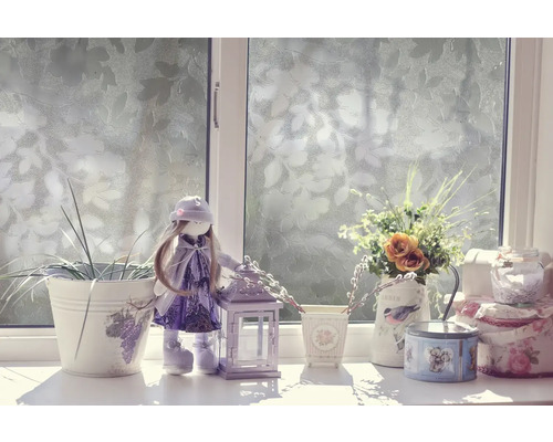 Dekorativ scen på en fönsterbräda med docka, lykta och blommor i vaser