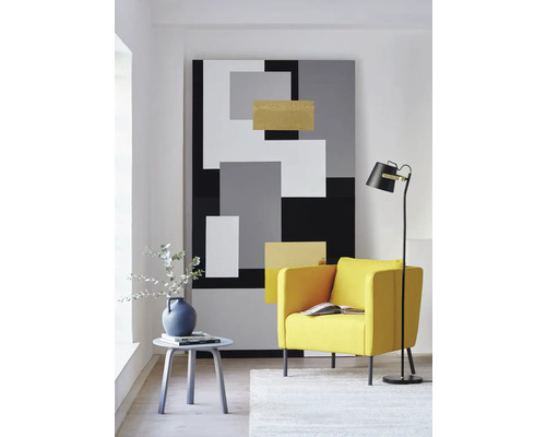 Vardagsrum med fåtölj, golvlampa, sidobord och abstrakt väggmålning i geometrisk design.