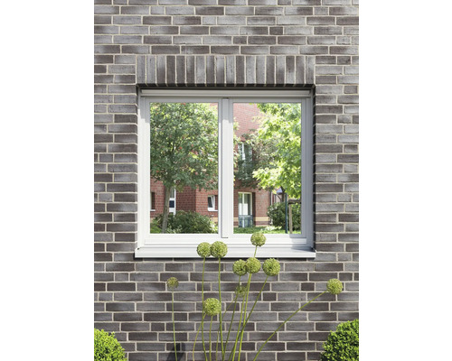 Fönster i en tegelvägg med utsikt över grönska