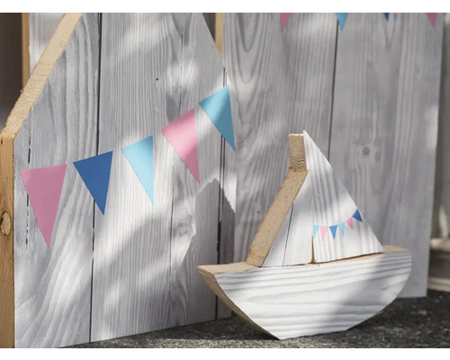 Dekorativ träbåt framför en trävägg med vimpelgirlang