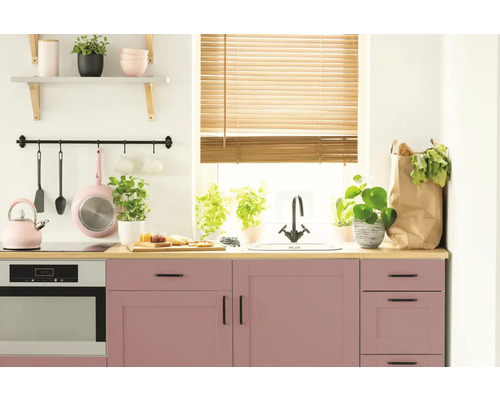 Ljust kök med rosa skåp, bänkskiva i trä och köksredskap