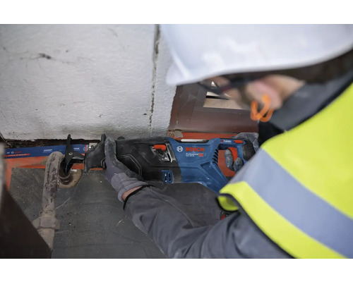 En byggnadsarbetare med skyddshjälm och skyddsväst använder en tigersåg av märket Bosch för att kapa ett rör.