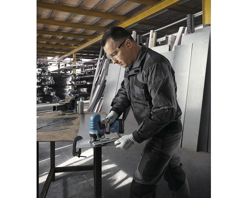 En man skär en metallplåt med en sladdlös sticksåg