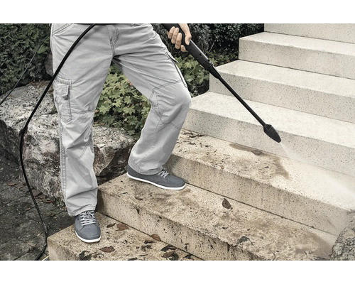 En person rengör stentrappor med en högtryckstvätt.