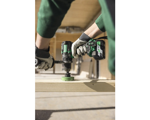 En person borrar ett hål i en träplanka med en sladdlös borrmaskin