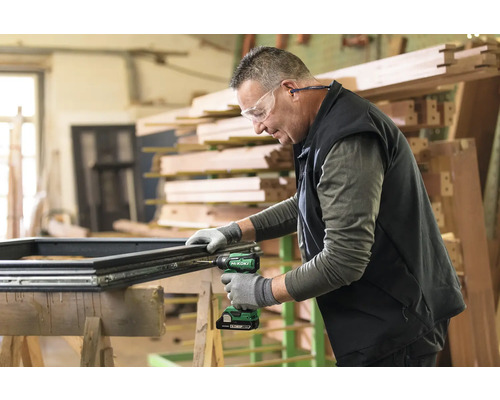 En hantverkare monterar ett fönster på en arbetsbänk med en sladdlös skruvdragare.