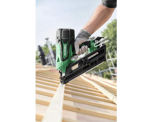 En person fäster en träplanka på en takstol med en grön HiKoki batteridriven spikpistol.