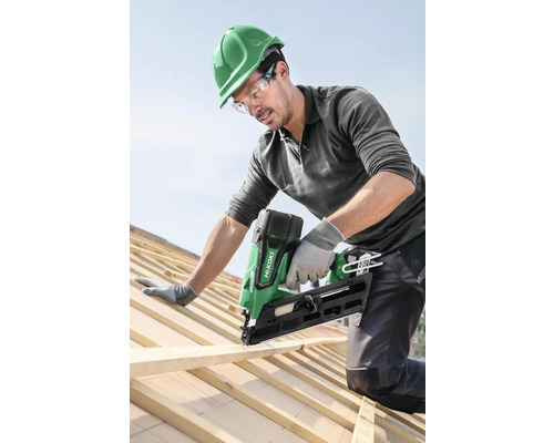 Hantverkare fäster träplatta med en batteridriven spikpistol på ett tak