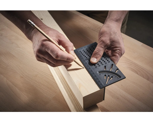 En person markerar en träplanka med en gradskiva och en penna.