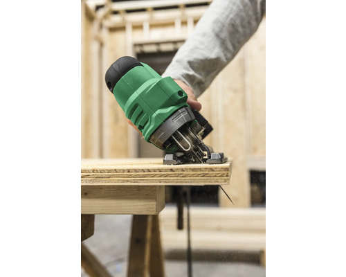 En sticksåg skär en träplanka på en arbetsbänk.