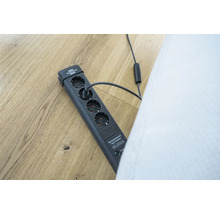 Grenuttag med överspänningsskydd och ansluten kontakt på ett trägolv