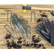 Trädgårdsbild med tältpinnar, gummiklubba och trädgårdshandskar på träbord