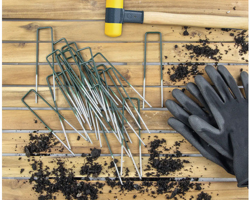 Trädgårdsbild med tältpinnar, gummiklubba och trädgårdshandskar på träbord