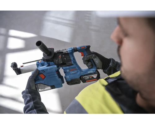 En arbetare håller en blå borrhammare från Bosch med ett 18 volts batteri.