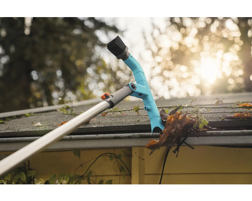 Takrännerengörare i arbete, tar bort löv och skräp från en takränna.