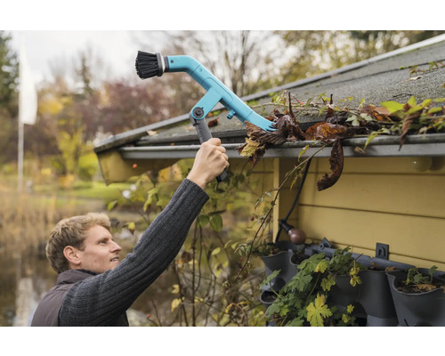 En person rengör en hängränna med en hängrännerengörare.