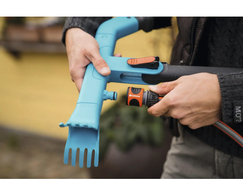 En person ansluter en Gardena slangkoppling till en Gardena ogrässtickare.