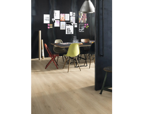 En matsal med trägolv, ett bord och diverse stolar mot en mörk vägg med anteckningar.