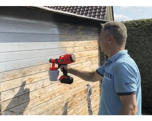 Man som målar en trävägg med ett färgspraysystem