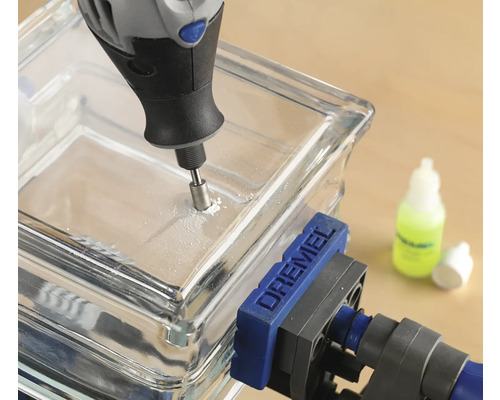 Dremel Logo. En glasplatta borras med ett Dremel multiverktyg och är fäst med en skruvtving.