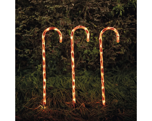 Tre upplysta polkagrisstänger som juldekoration i trädgården.