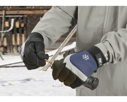 En person bär arbetshandskar och håller i en borrmaskin.