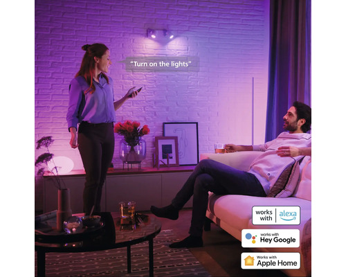 Vardagsrum med två personer som använder smart hembelysning med röststyrning